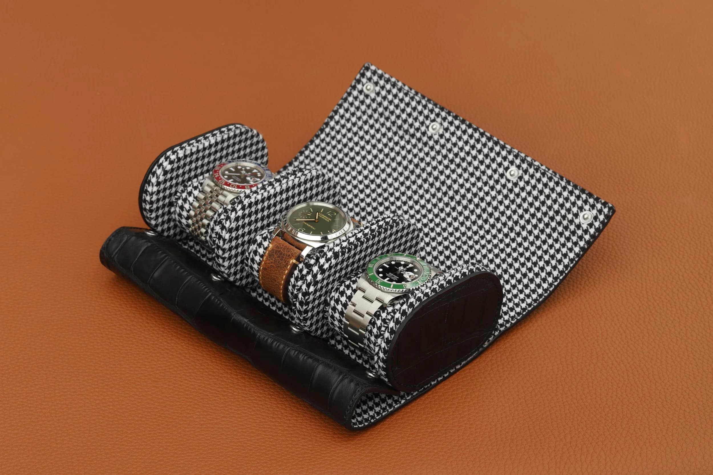 A leather watch roll holding three watches.