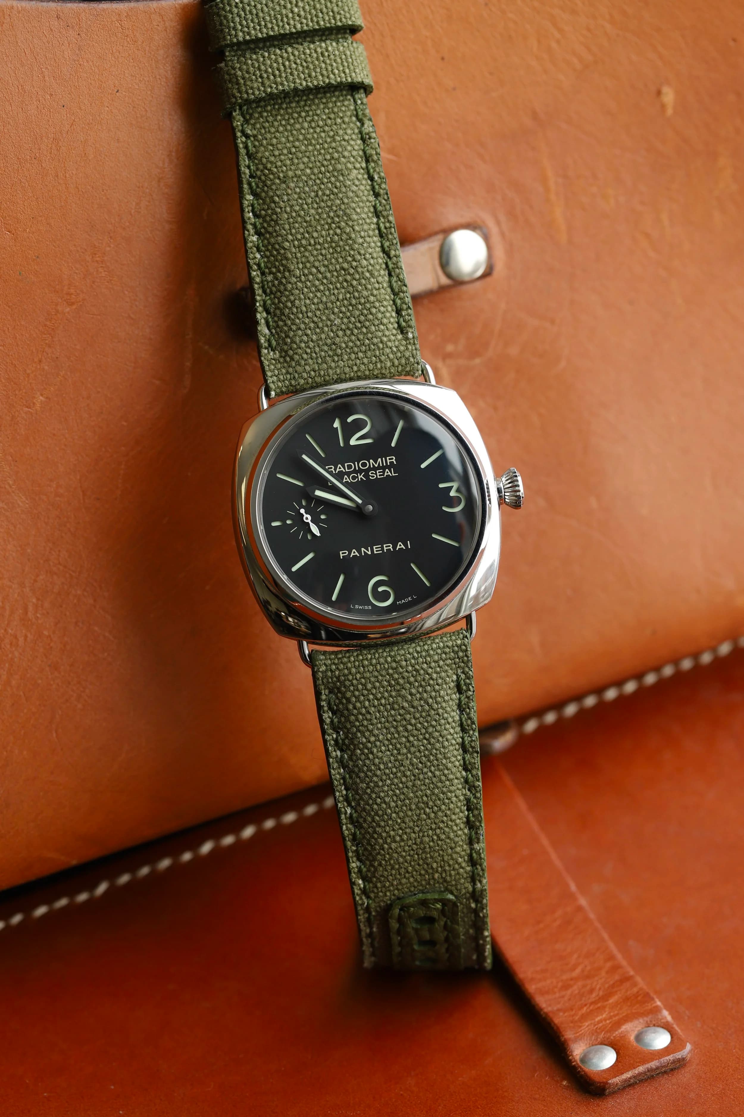 A Panerai Radiomir on a hand-stitched olive canvas strap, on tan leather.