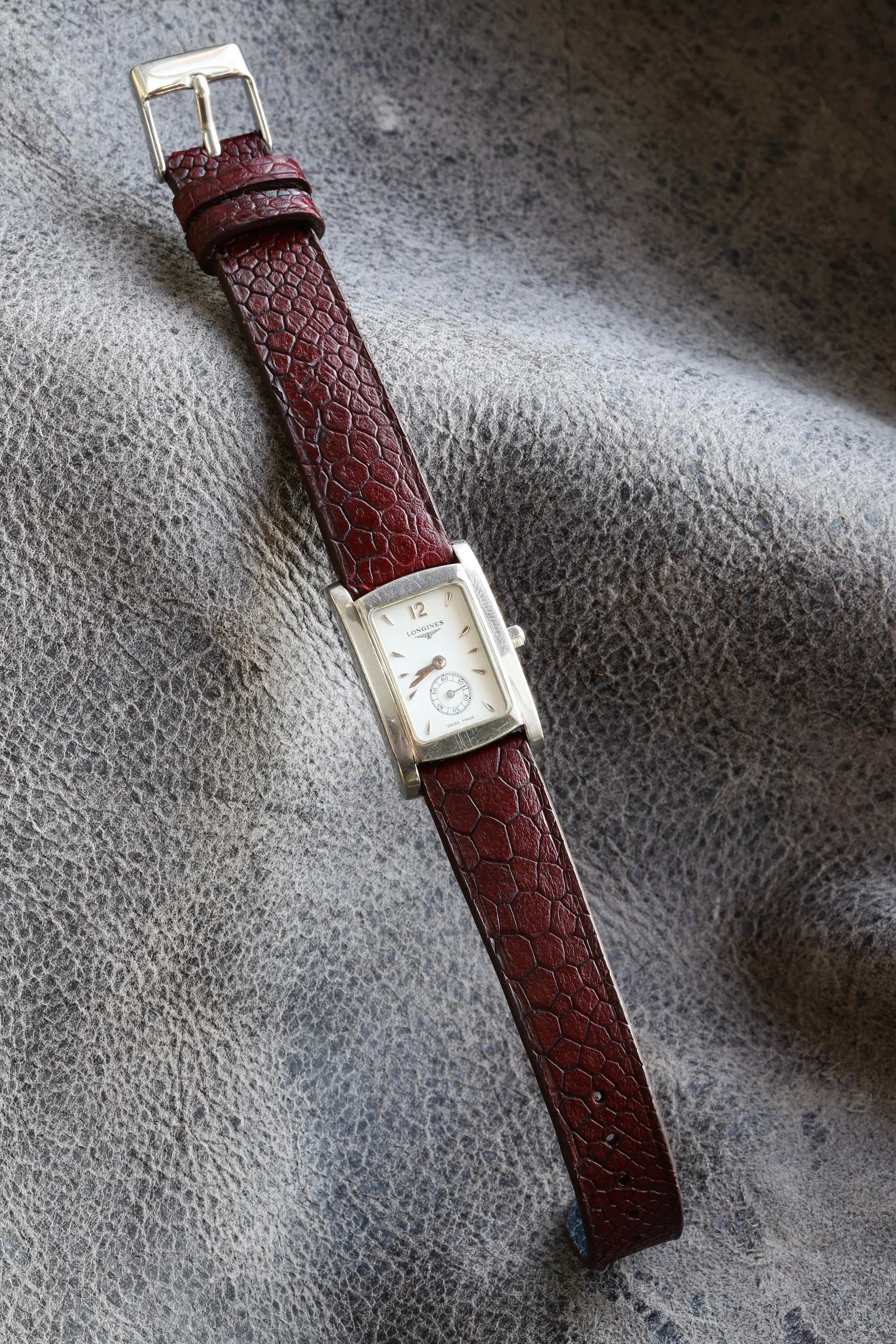 A vintage gold pin buckle on a burgundy French-patina strap.